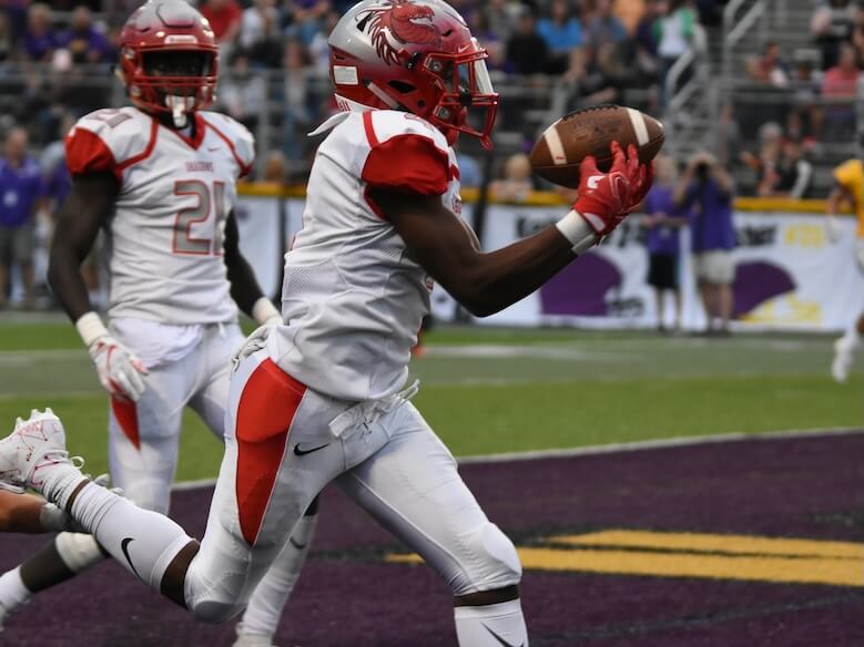 man catching football on field at daytime