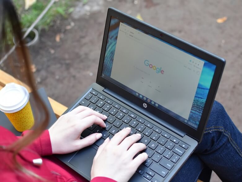 a woman sitting on a bench using a laptop computer