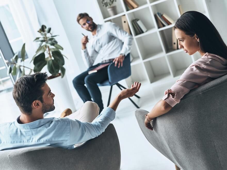 young married couple talking while sitting on the therapy session with psychologist