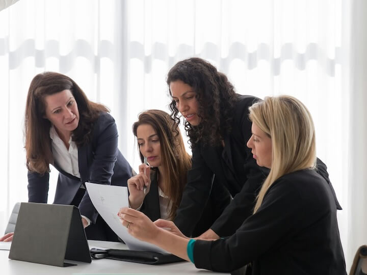 women in blazers having a meeting in an office