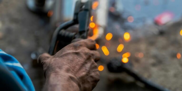 a man holding a welding gun in his right hand FEATURED IMAGE