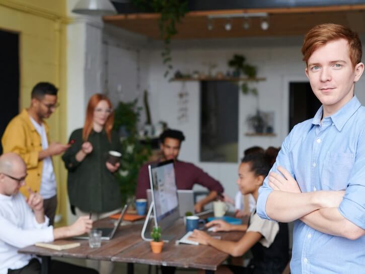 Man Standing Beside People Sitting Beside Table With Laptops