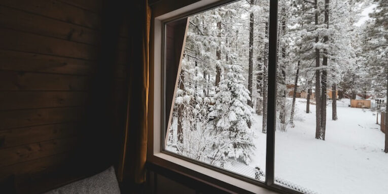 a window with a view of a snowy forest FEATURED IMAGE