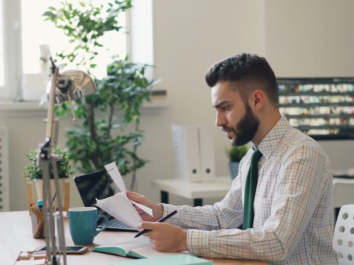 a man sitting at a desk with a laptop and papers