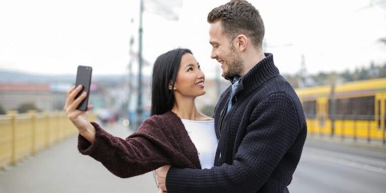 Selective Focus Photo of Happy Couple Hugging While Taking a Selfie FEATURED IMAGE