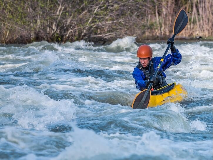 Photo of Man Paddling Kayak in Raging River
