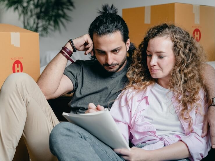 Thoughtful couple writing in notebook while moving house