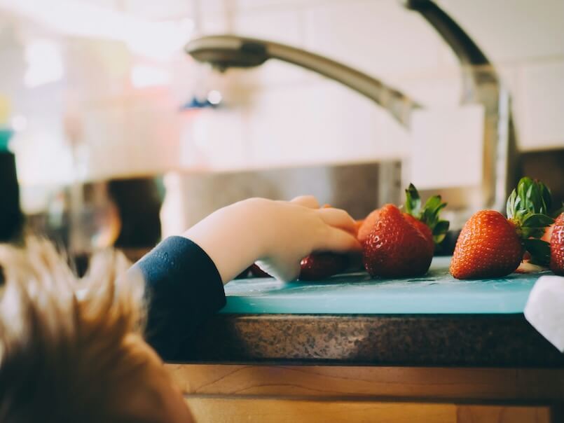 child picking strawberries in kitchen
