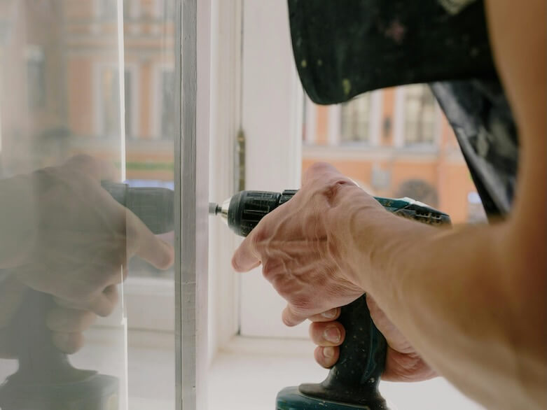 Crop man screwing metal detail on window

