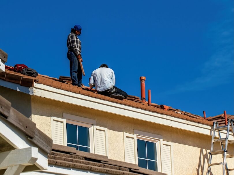 Low Angle Shot of Builders Fixing a Tiled Roof against Blue Sky
