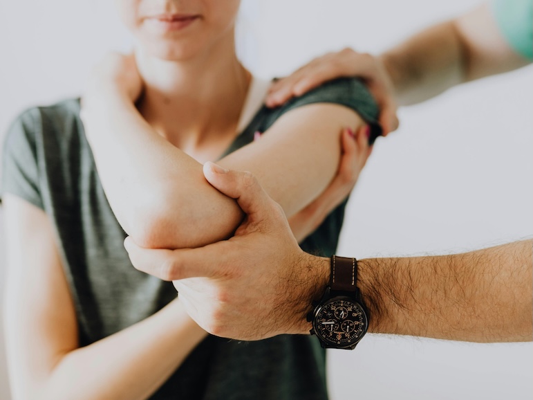Crop unrecognizable chiropractor examining arm joint of female patient
