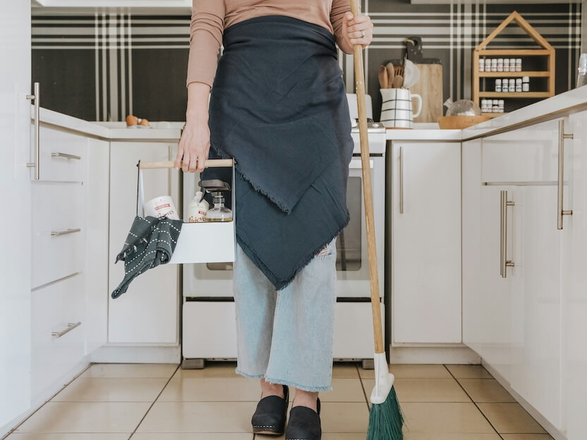 a woman standing in a kitchen holding a broom