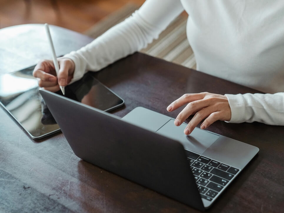 Crop faceless female entrepreneur doing multitasking work on different devices
