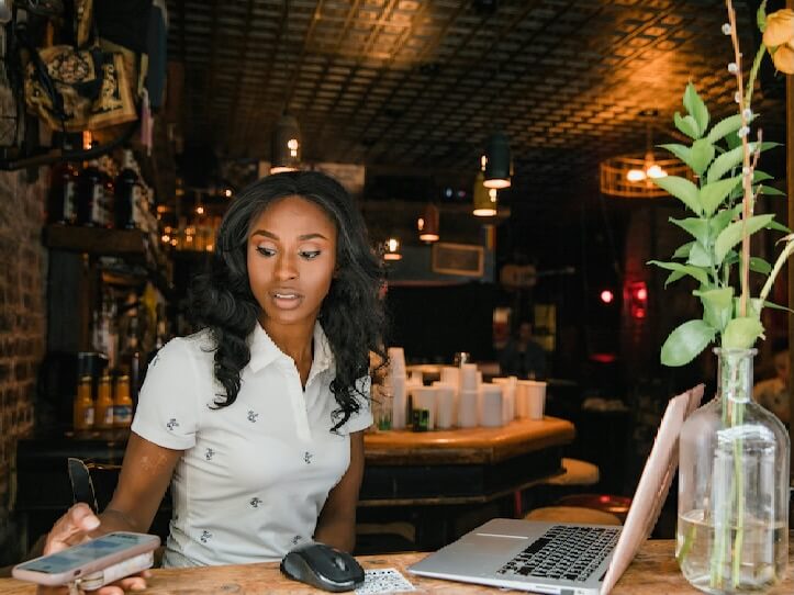 Woman Using Laptop and Smart Phone at Cafe
