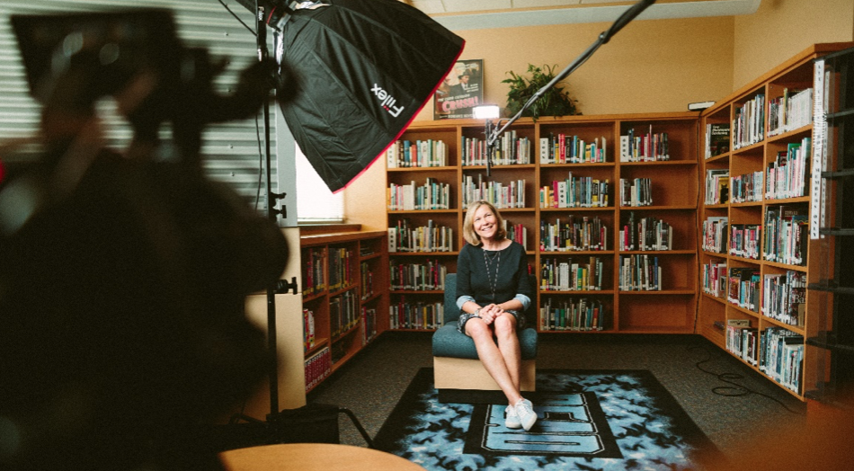 woman sitting on armless chair with light between bookcases in room