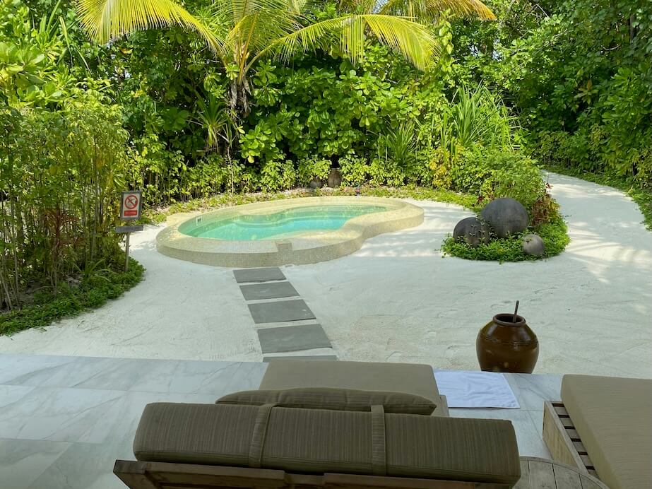 a patio with a pool surrounded by greenery
