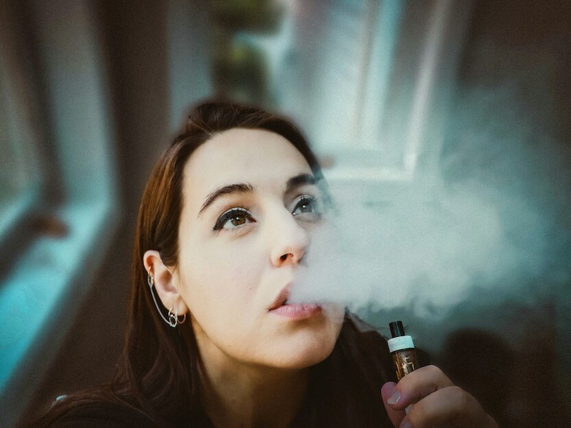 woman holding black and gold tube type vape