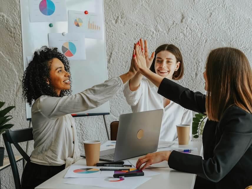 Beautiful Women Sitting at a Table Giving High Five