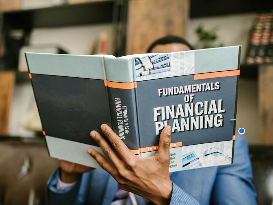 Person Reading a Book About Fundamentals of Financial Planning
