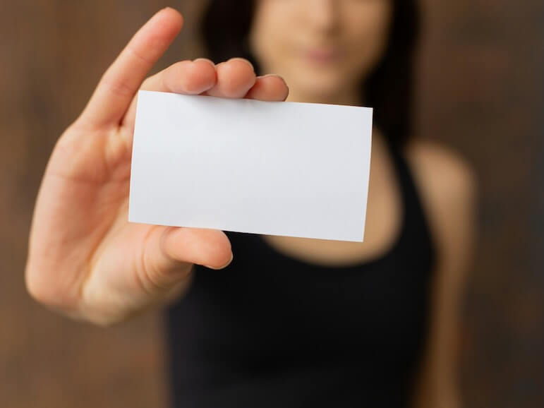 Crop woman showing blank business card