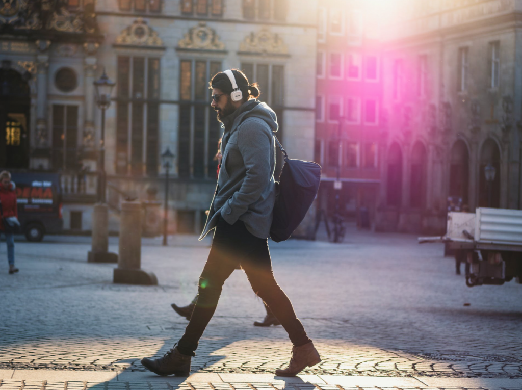 Man in Gray Hooded Jacket Walking on Gray Bricks Pavement