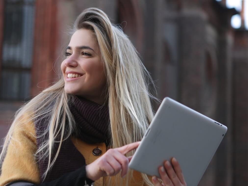 Woman in Brown Coat Holding Silver Ipad