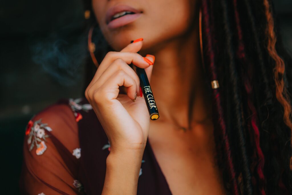 woman holding black and purple vape pen