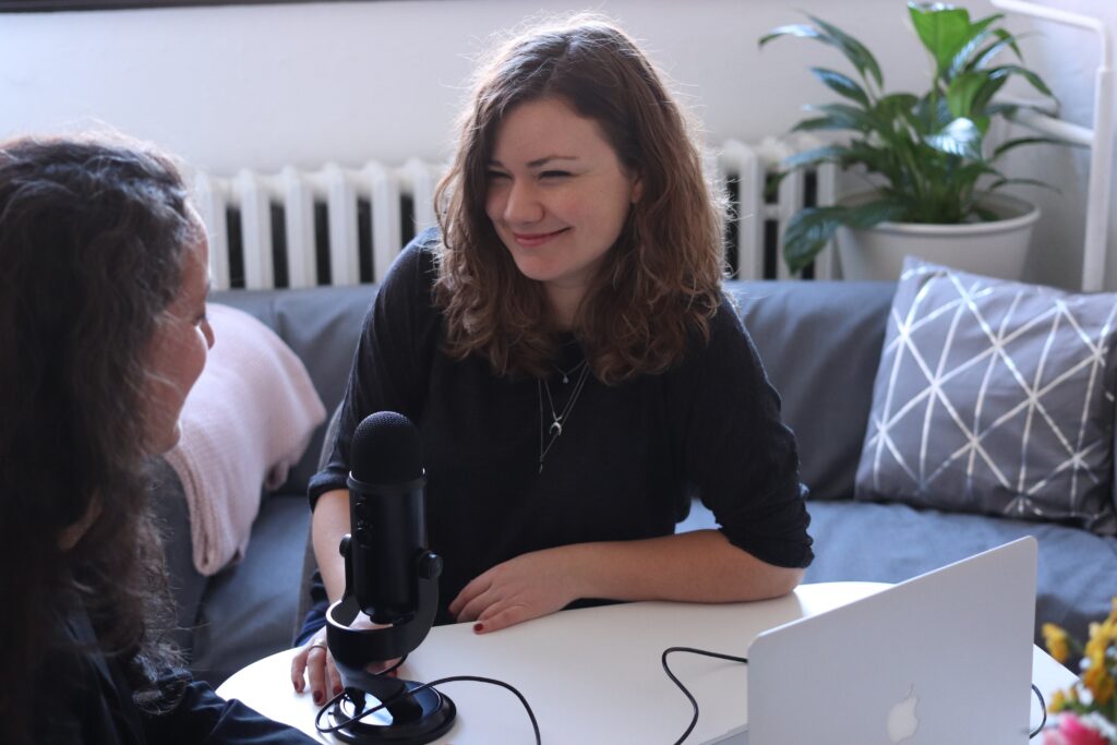woman in black half sleeved shirt sitting while facing woman and smiling