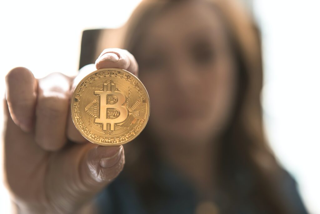 woman holding up a bitcoin - cryptocurrency