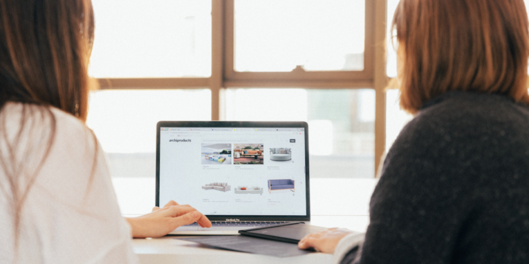 two women talking while looking at laptop computer FEATURED IMAGE