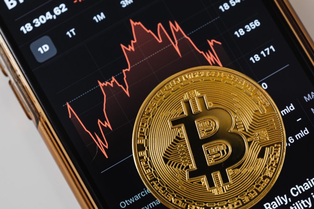 Close-up of a Bitcoin Coin Lying on a Screen Displaying a Stock Market Chart