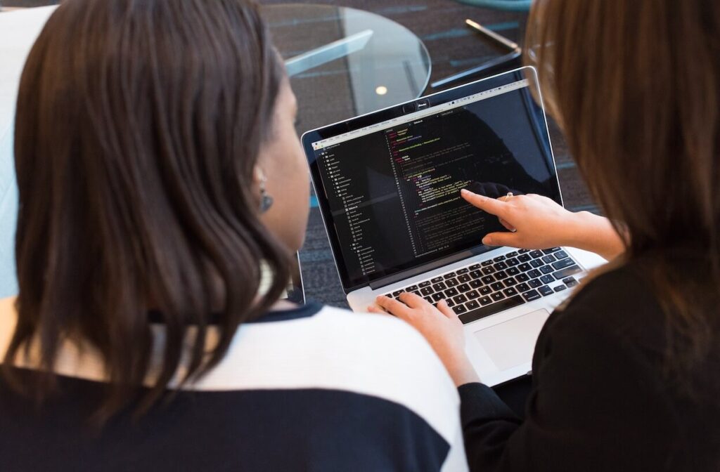 Google BigQuery, Two Women Looking at the Code at Laptop