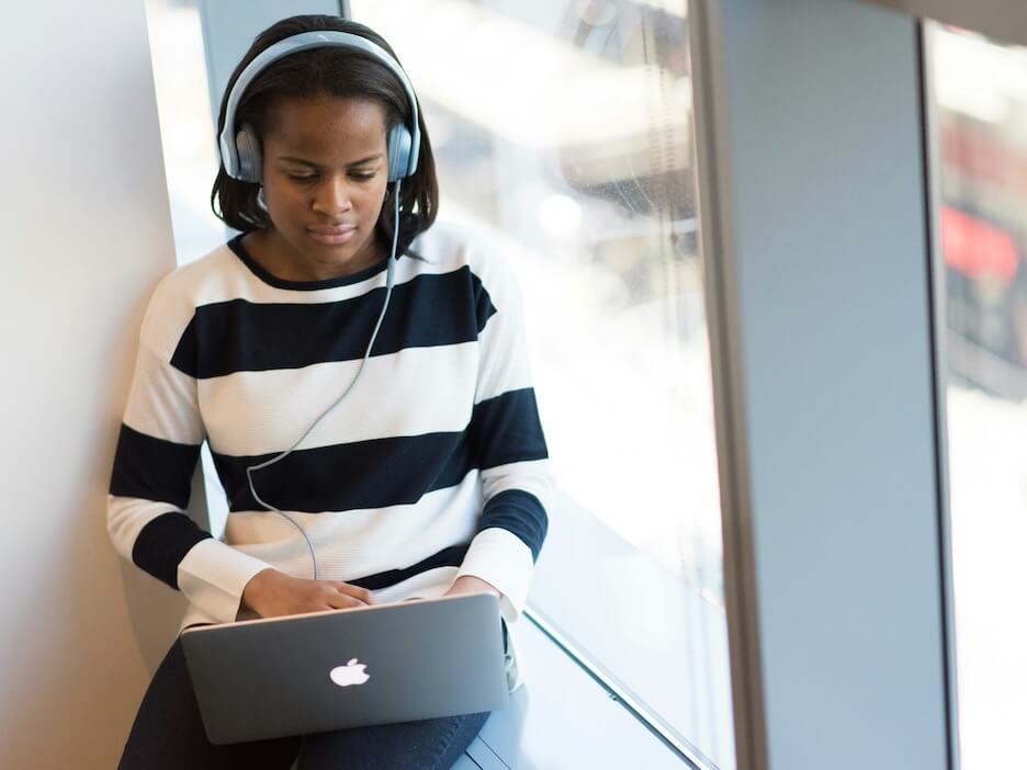 woman writing with headphones on