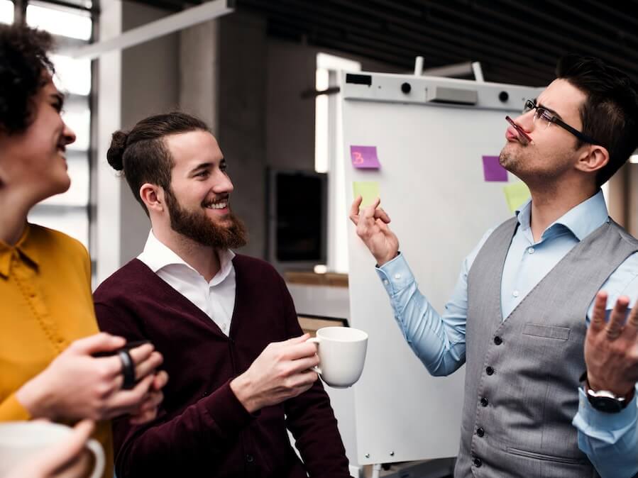a group of cheerful young business people with cup of coffee standing