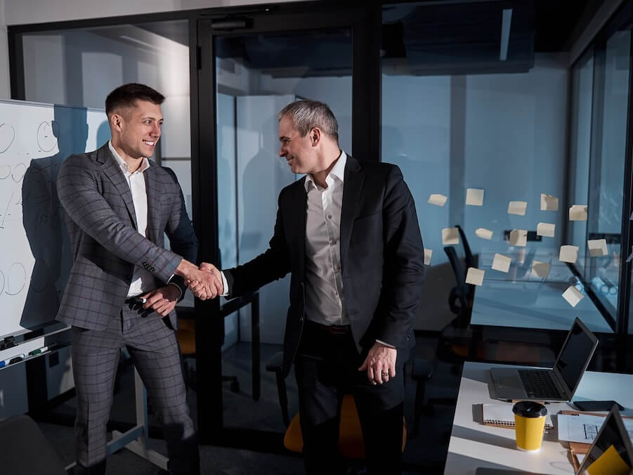 joyful businessmen standing shaking hands