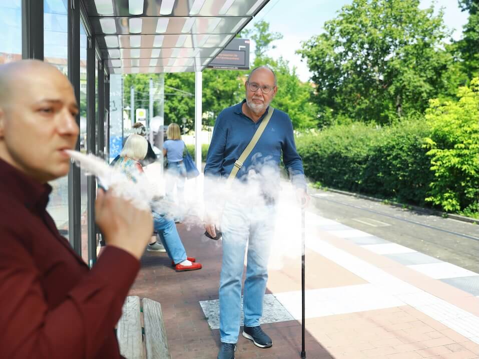 a man smoking a cigarette in front of a bus stop