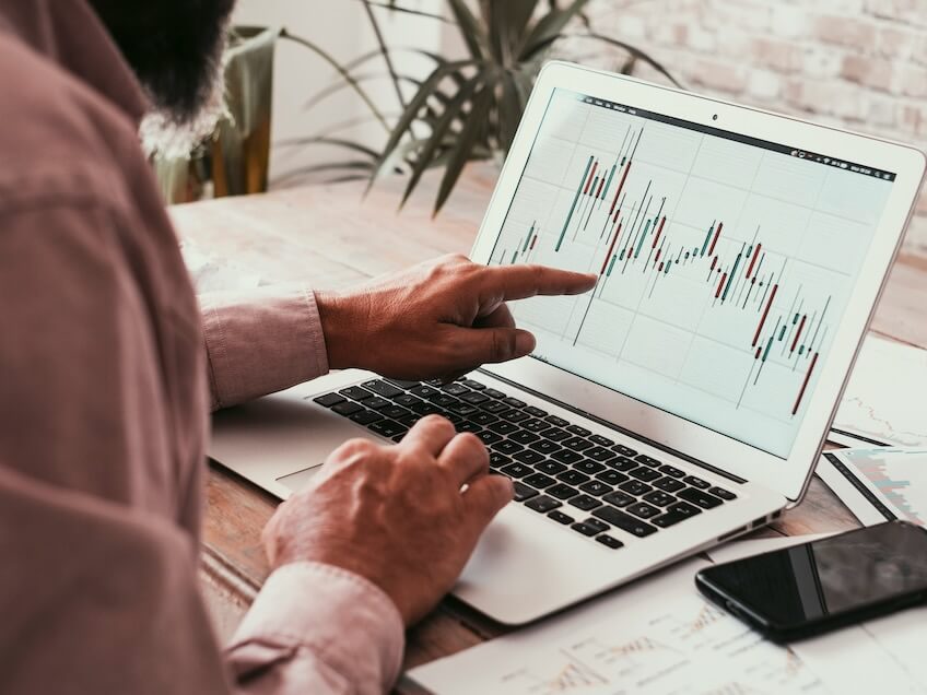 back view of man reading forex chart on laptop display