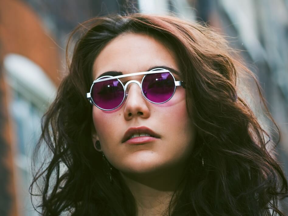 a woman wearing sunglasses standing in front of a-building