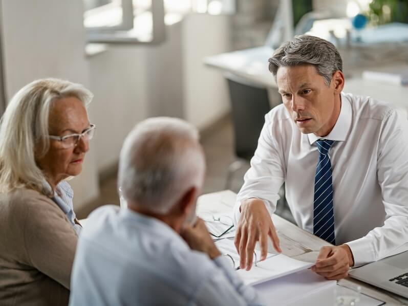 financial advisor discussing with senior couple about their financial reports during consultations in the office