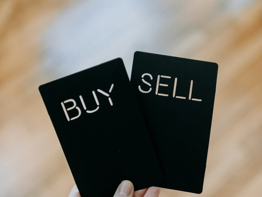 a hand holding two black cards with the words buy and sell wrritten on them