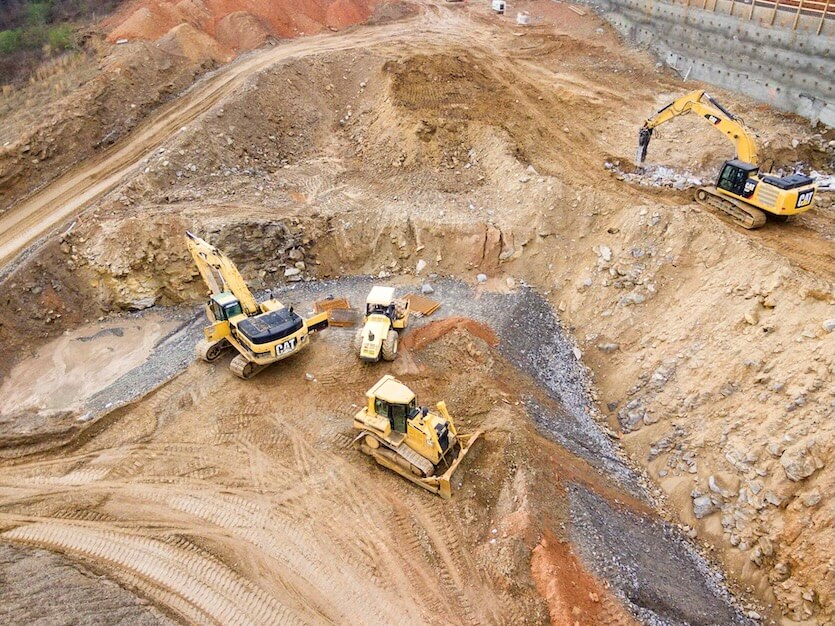 top view photography of four heavy equipment on quarry at daytime