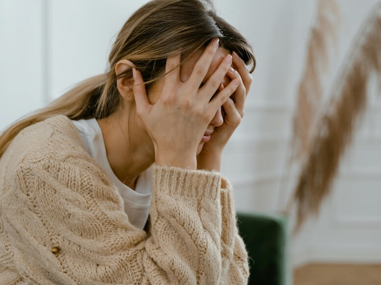 Woman Sitting with Hands Covering Her Face