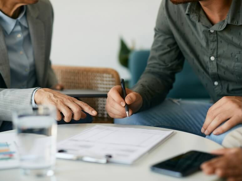 close up of couple closing a deal with their financial advisor and signing paperwork during the meeting