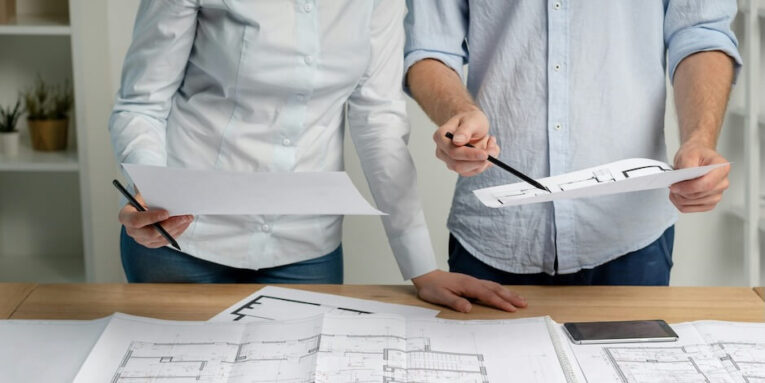 FEATURED IMAGE: cropped photo group of two person in formalwear shirt stand at the table in light loft interior workplace make modern renovation look at blank on room pointer on structure document by pencil