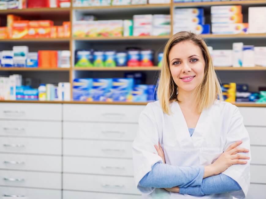 portrait of a young beautiful friendly female pharmacist arms crossed - FEATURED IMAGE
