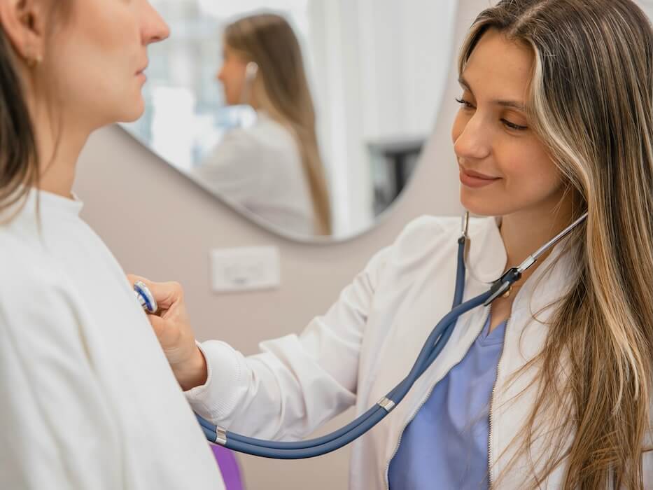 a woman in a white lab coat is listening to a woman in a white coat