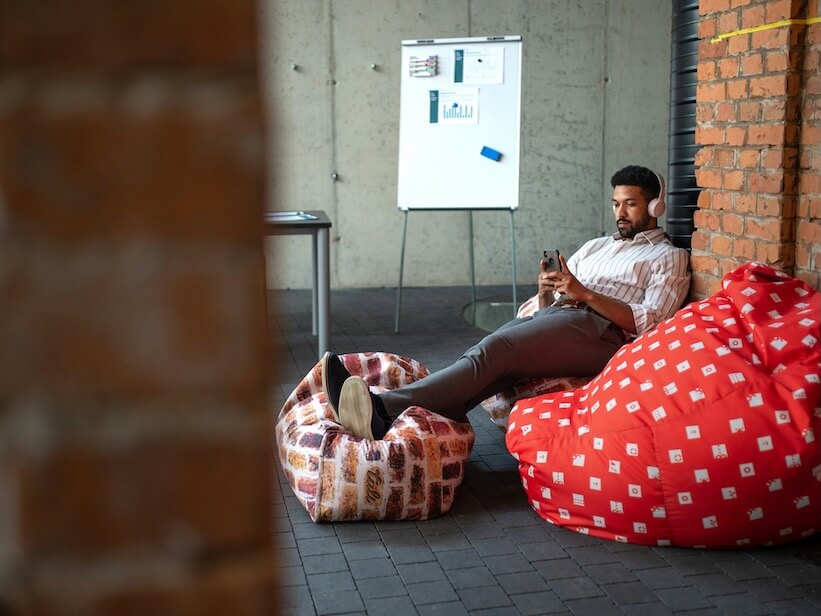 young businessman with smartphone and headphones taking a break in an office resting