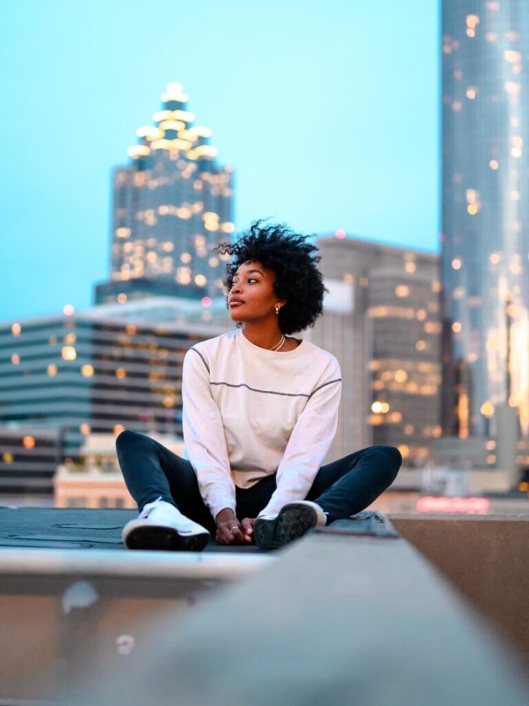 woman in white shirt and black pants sitting on gray concrete bench