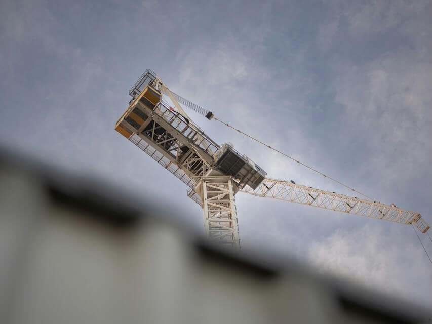 a tower crane is seen against a cloudy sky