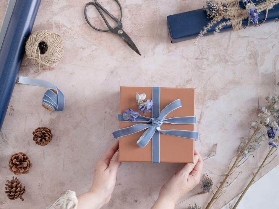 a person holding a wrapped gift box with a blue ribbon